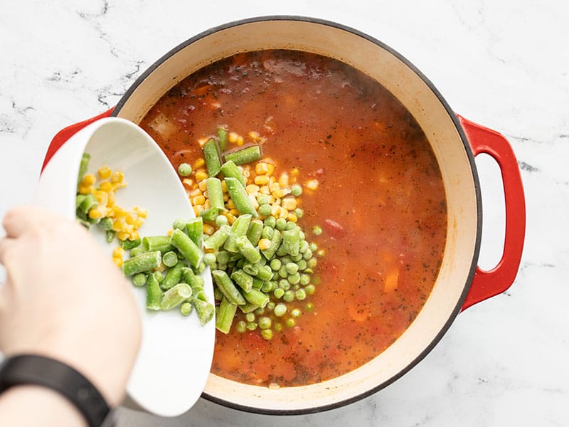 Frozen vegetables being poured into the soup