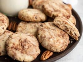 Close up of Cinnamon Pecan Sandies on a wooden plate with whole pecans
