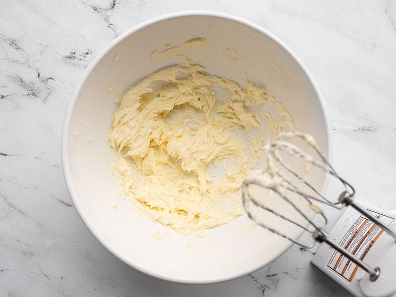 Creamed butter and sugar in a bowl with mixer beaters hovering over bowl