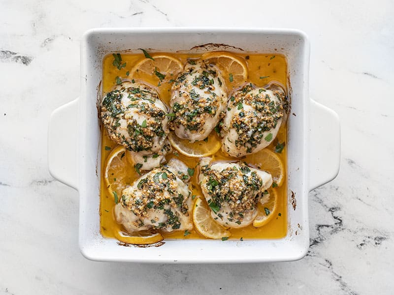 Baked garlic butter chicken thighs in the baking dish with fresh parsley