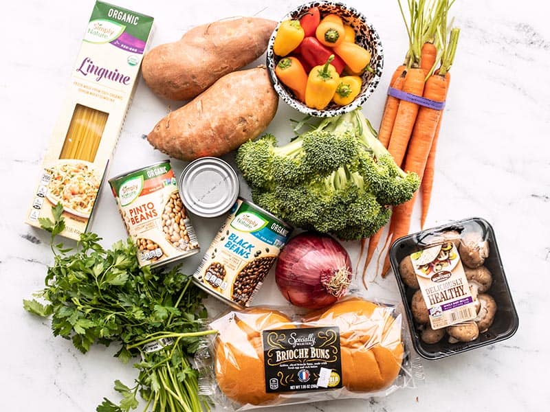 Groceries laid out on a surface, including vegetables, canned goods, and pasta