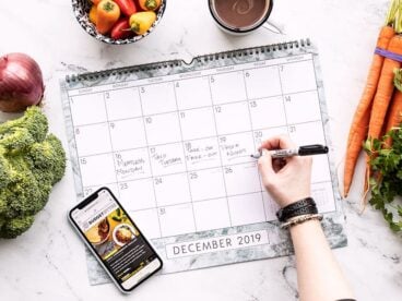 A hand writing on a calendar surrounded by fresh produce