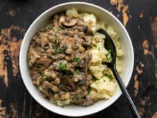 Overhead view of a bowl of mashed potatoes topped with lentils in a creamy mushroom gravy