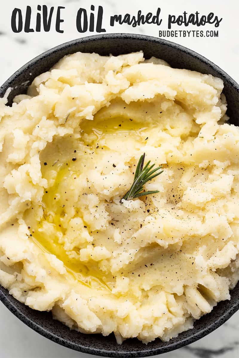 Close up overhead view of a bowl of Olive Oil Mashed Potatoes garnished with rosemary and olive oil