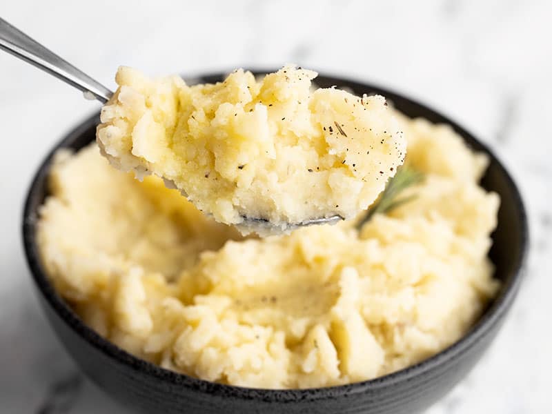 A big scoop of Olive Oil Mashed Potatoes being lifted from the bowl