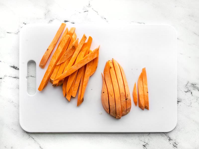 Sliced sweet potatoes into fries on cutting board