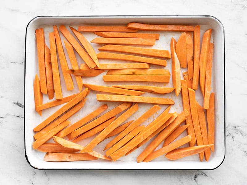 Cut sweet potatoes arranged on the baking sheet