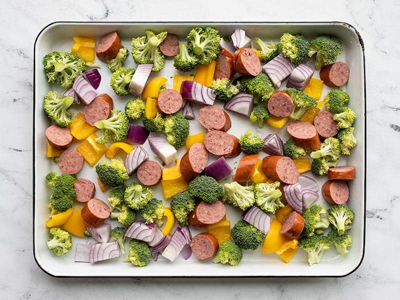 Chopped vegetables and sliced sausage on the baking sheet