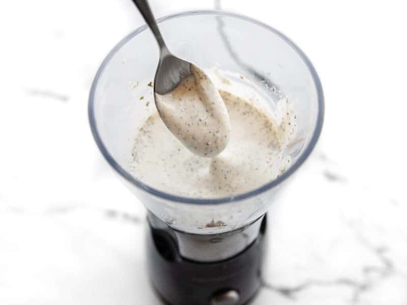 A spoon lifting some whipped cottage cheese dip out of the blender