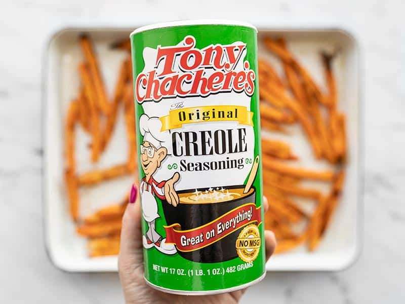 Creole seasoning bottle held above the baking sheet