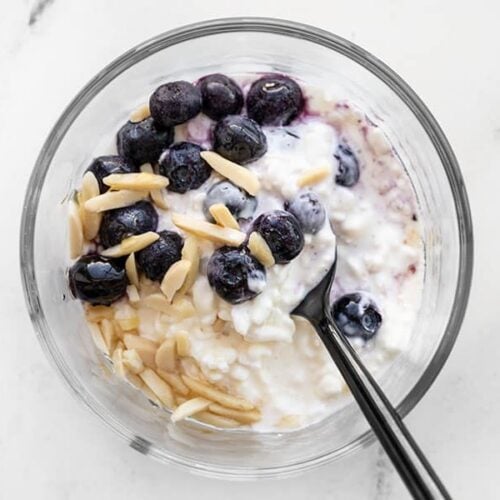 Cottage cheese, blueberries, sliced almonds, and honey in a glass meal prep container