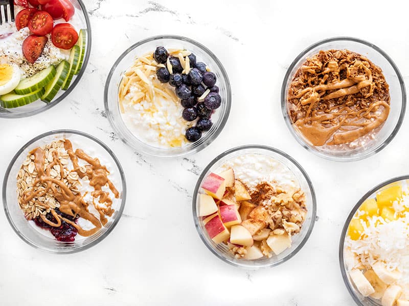 Six glass bowls with different flavors of cottage cheese breakfast bowls inside.