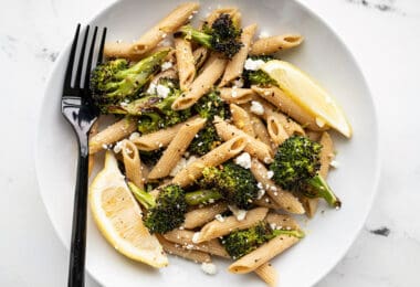 A bowl full of Roasted Broccoli Pasta with lemon and feta and a black fork on the left side