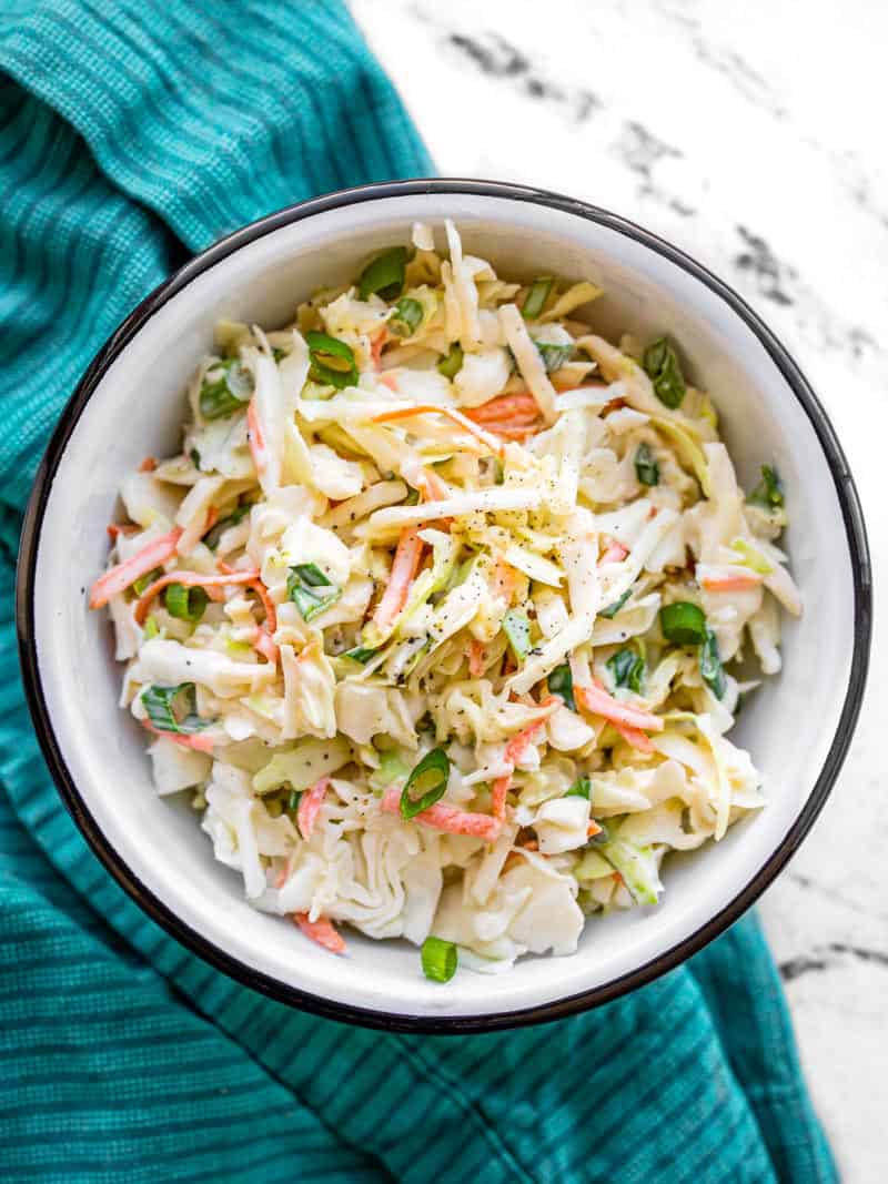 Overhead view of a bowl of coleslaw on a blue napkin