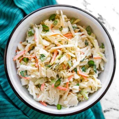 Overhead view of a bowl of creamy coleslaw on a blue napkin