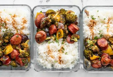 Three glass meal prep containers with rice and Smoky Roasted Sausage and Vegetables