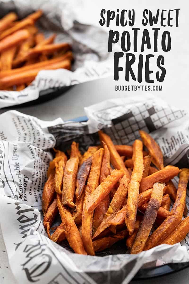 Two bowls lined with newsprint and full of spicy sweet potato fries