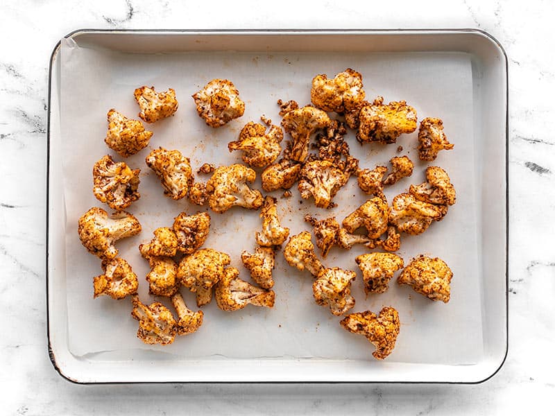 Seasoned cauliflower on baking sheet covered with parchment paper