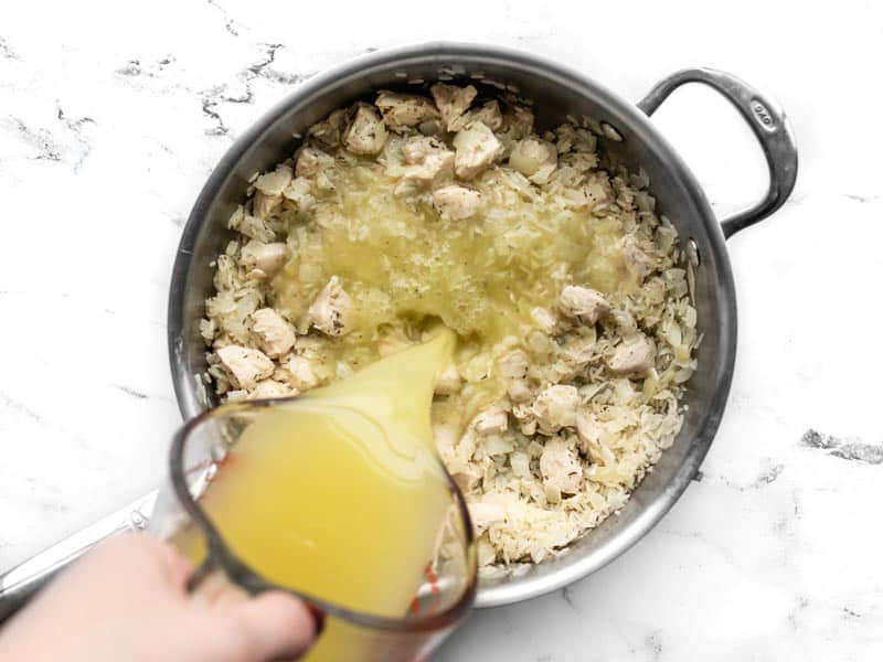 Chicken broth being poured into the skillet
