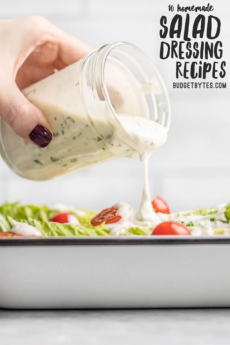 Ranch dressing being poured from a jar onto a salad