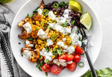 Close up overhead view of a roasted cauliflower taco bowl topped with cilantro lime ranch and a black fork in the middle