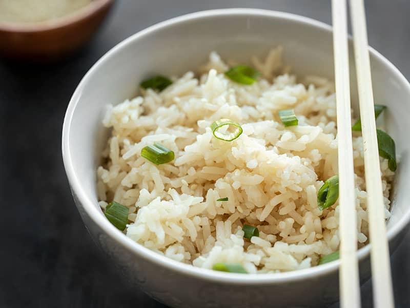 Close up side view of a bowl full of sesame rice garnished with green onions