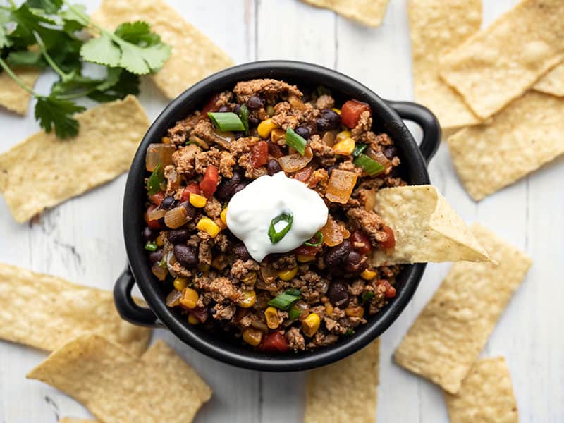 Turkey taco skillet in a small bowl with tortilla chips for dipping
