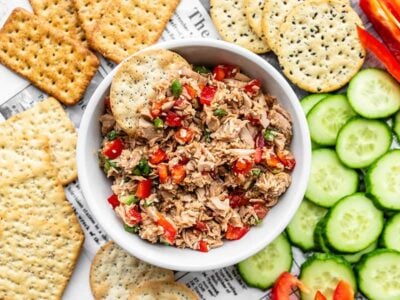 A bowl of Sesame Tuna Salad surrounded by crackers and cucumber slices