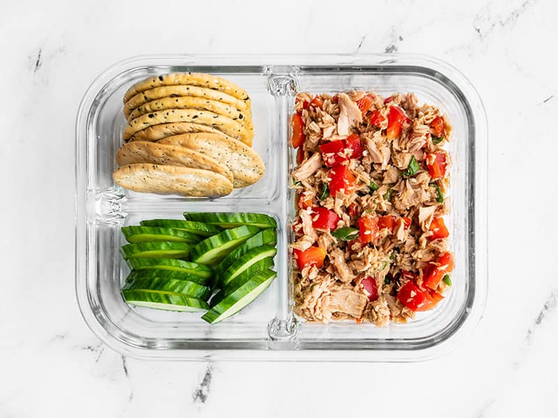 Meal prep container filled with Sesame Tuna Salad, crackers, and cucumber slices