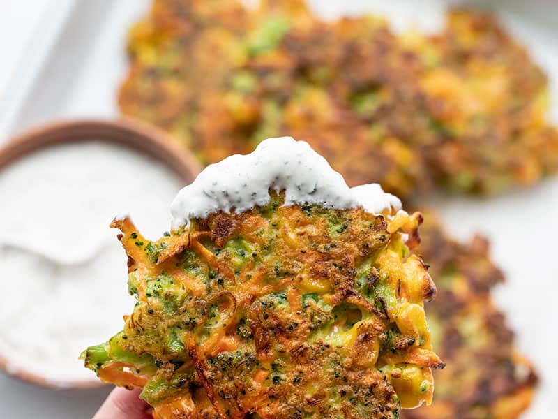 Close up of a vegetable fritter that has been dipped in the garlic herb sauce.
