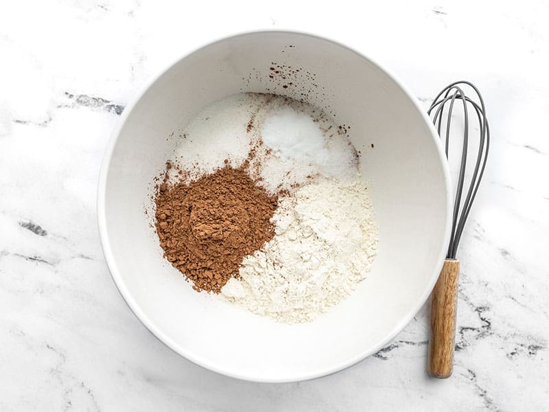 Chocolate cake dry ingredients in a bowl with a whisk on the side