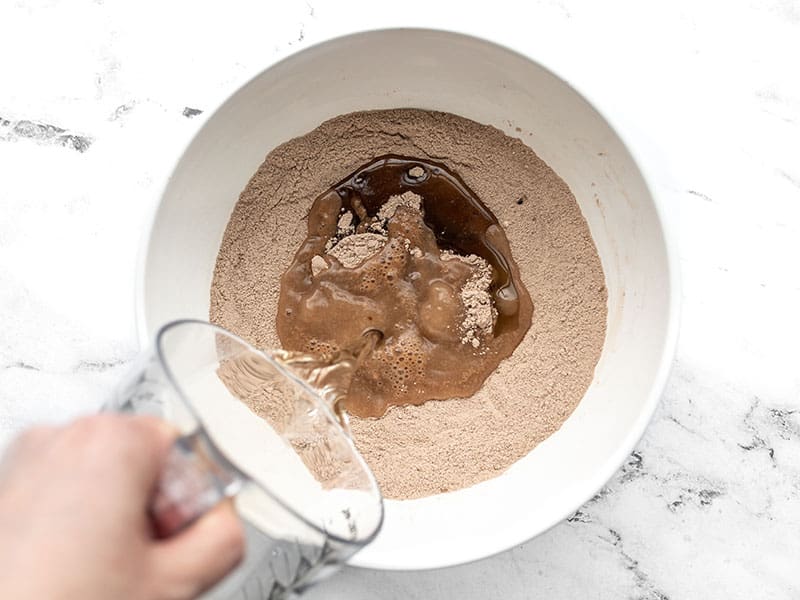 Wet ingredients being poured into dry ingredients in the bowl