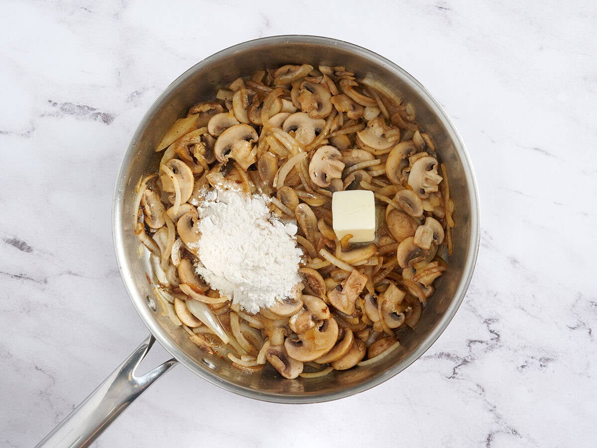 Butter and flour added to a skillet with sliced mushrooms and onions.