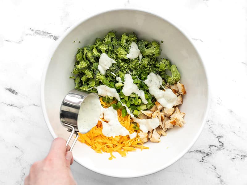 Ranch dressing being drizzled over the salad ingredients in the bowl