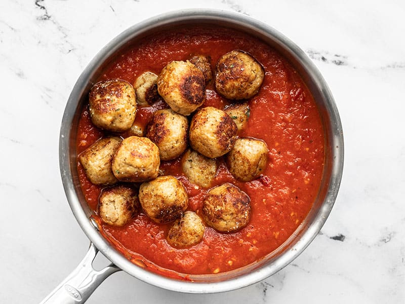 Cooked meatballs added to pot of pasta sauce