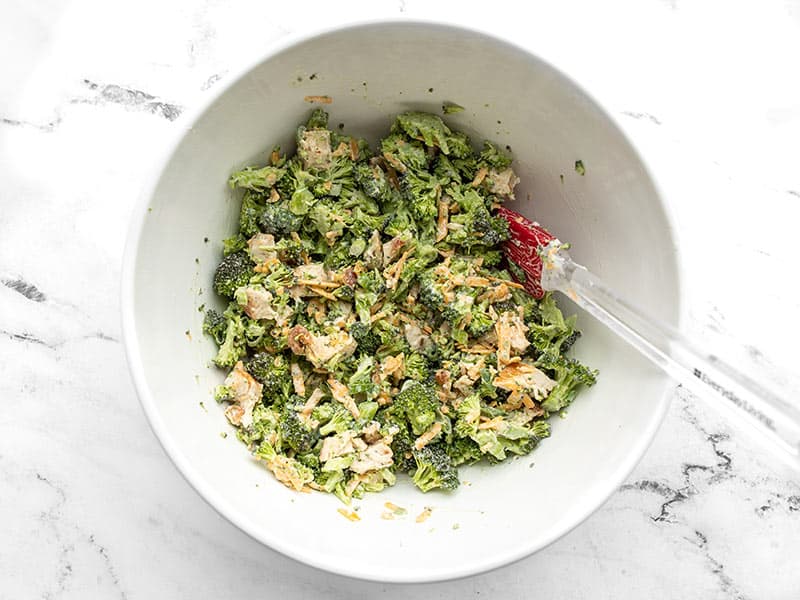 Finished broccoli cheddar chicken salad in the bowl with a spatula