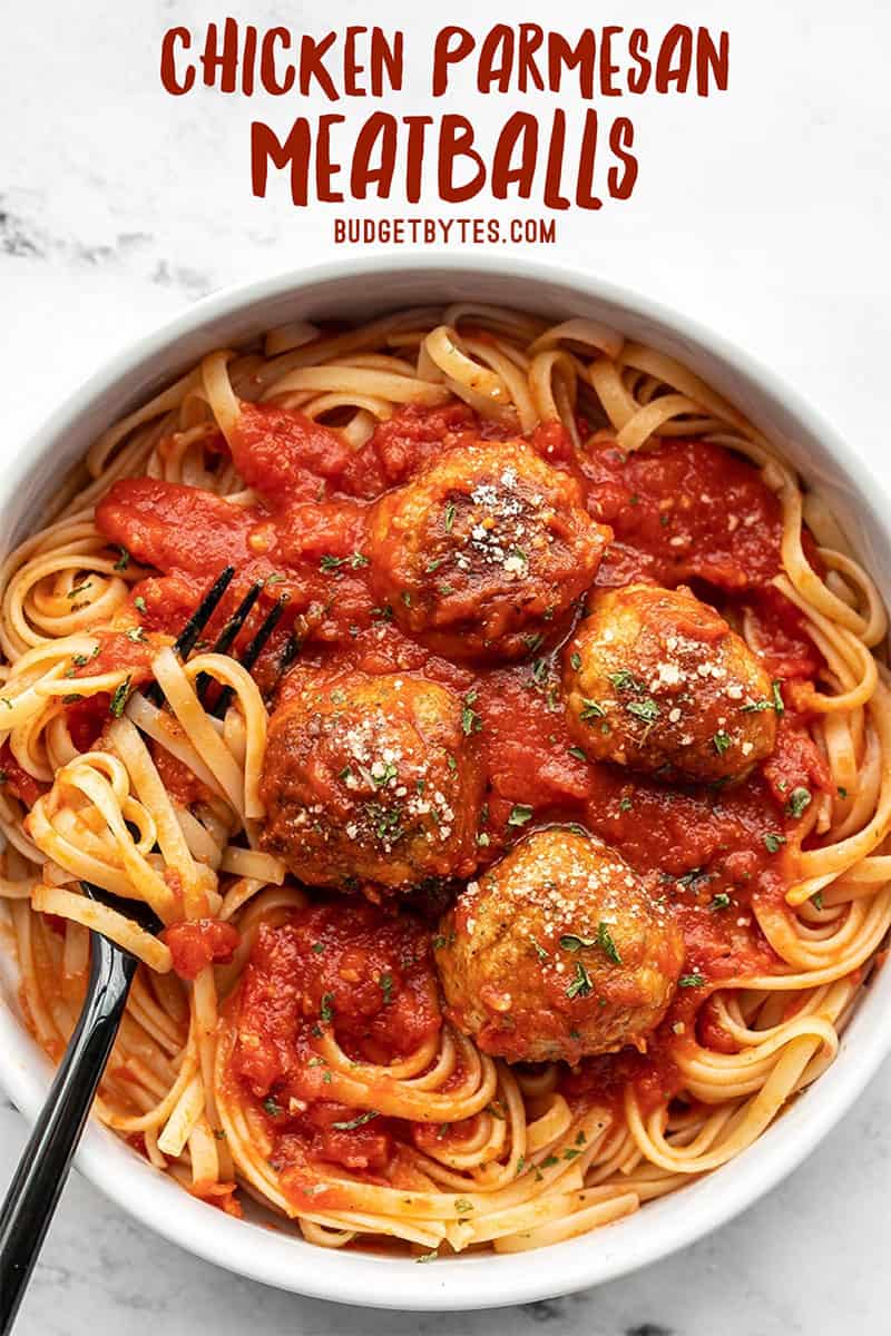 Overhead view of a bowl full of spaghetti with sauce and Chicken Parmesan Meatballs, a fork in the side.