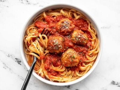 A bowl full of spaghetti with sauce and Chicken Parmesan Meatballs, with a fork in the side.