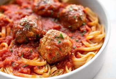 Close up side view of chicken Parmesan meatballs on a pile of spaghetti with sauce