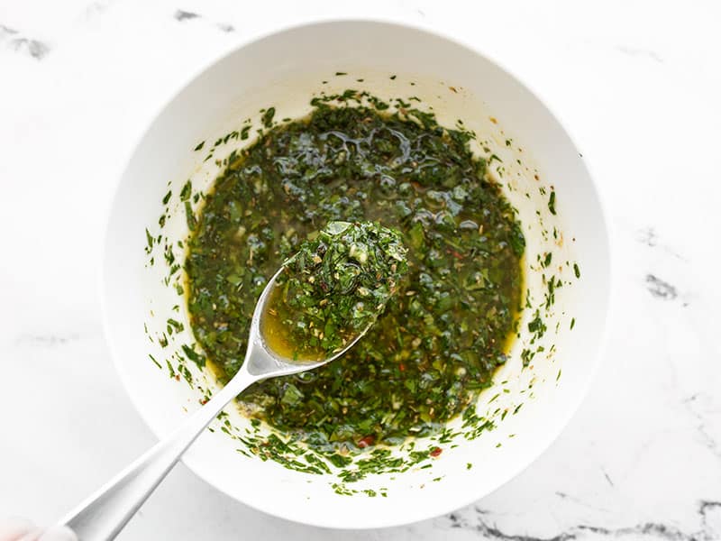 Mixed chimichurri in a bowl with a spoon