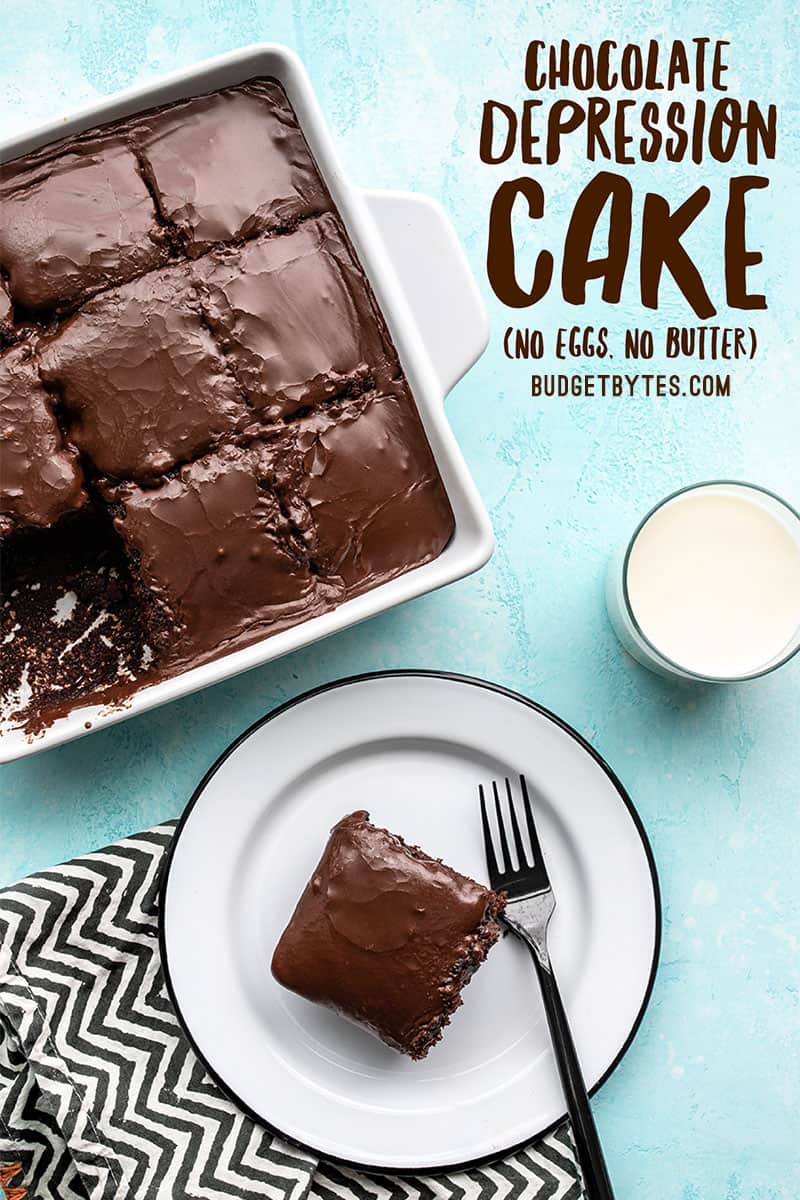 A chocolate depression cake cut into 9 pieces, one piece served on a white plate. A glass of milk on the side.