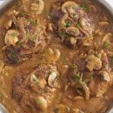 Overhead view of Salisbury steak in a skillet with mushroom gravy.
