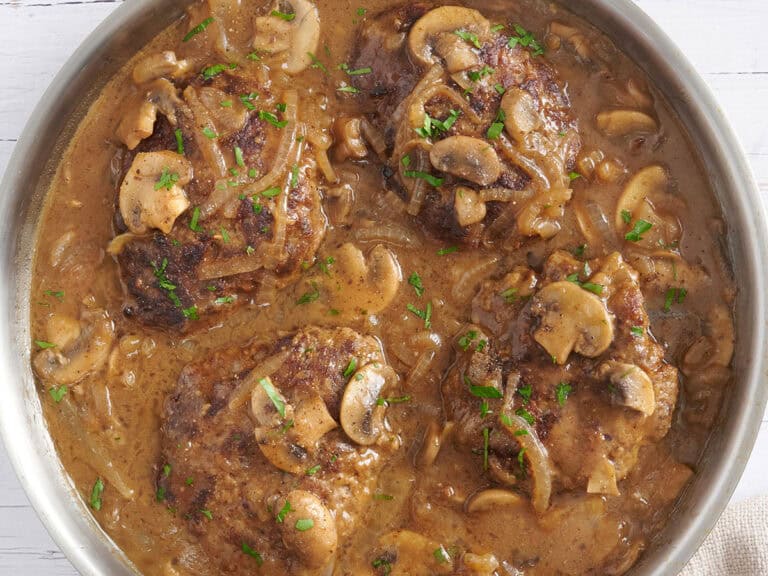 Overhead view of Salisbury steak in a skillet with mushroom gravy.