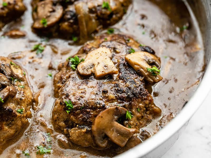 Close up side view of the Salisbury Steak in the skillet with mushroom gravy.