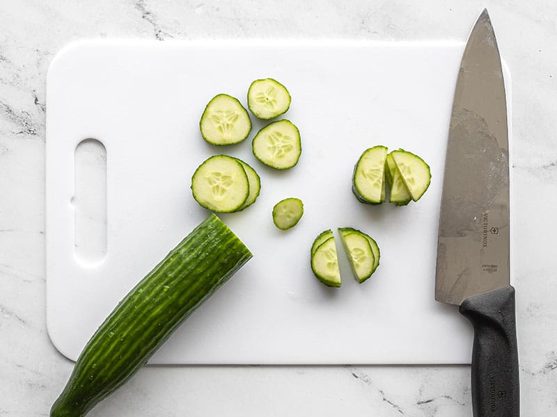 Sliced cucumber on a cutting board with a knife