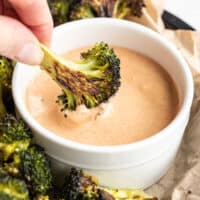 Close up of broccoli being dipped into comeback sauce