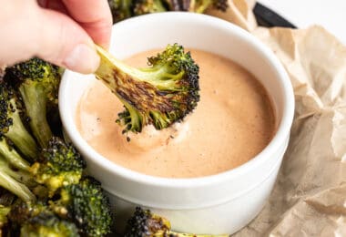 Close up of broccoli being dipped into comeback sauce