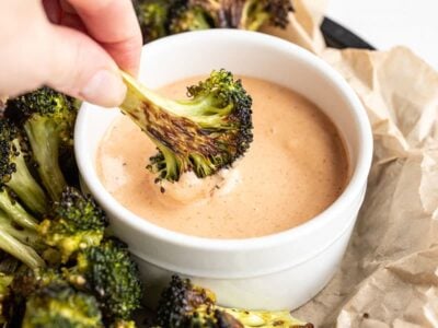 Close up of broccoli being dipped into comeback sauce
