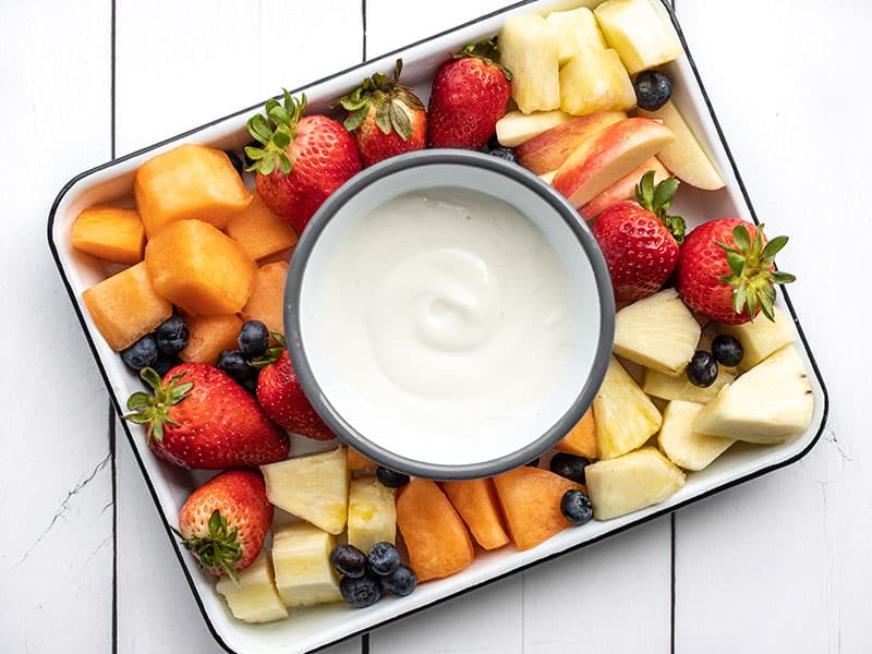 A bowl of cottage cheese fruit dip in the middle of a fruit platter