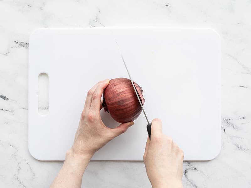 Root end of a red onion being cut off